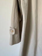 Close-up of beige trench with a button on a white background