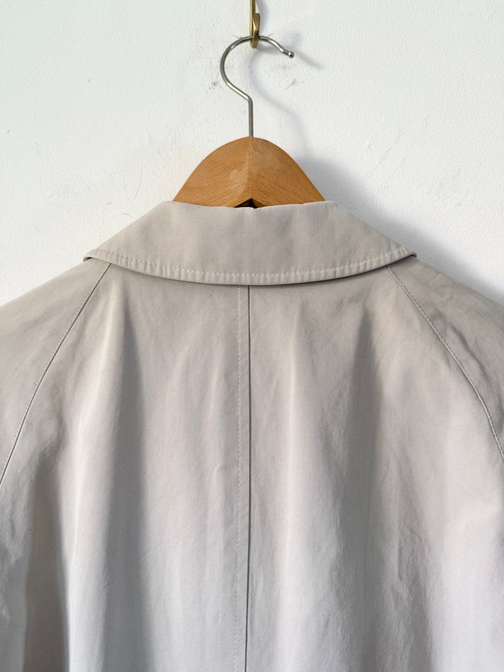 Trench coat on a wooden hanger against a white background