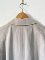 Trench coat on a wooden hanger against a white background