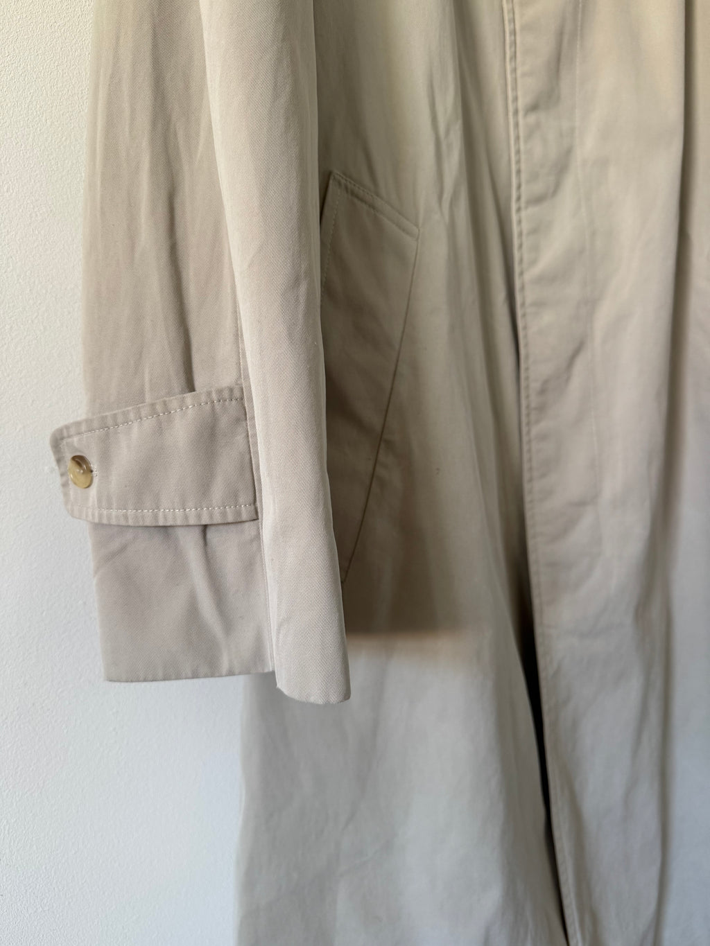 Close-up of beige trench with a button on a white background