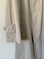Close-up of beige trench with a button on a white background