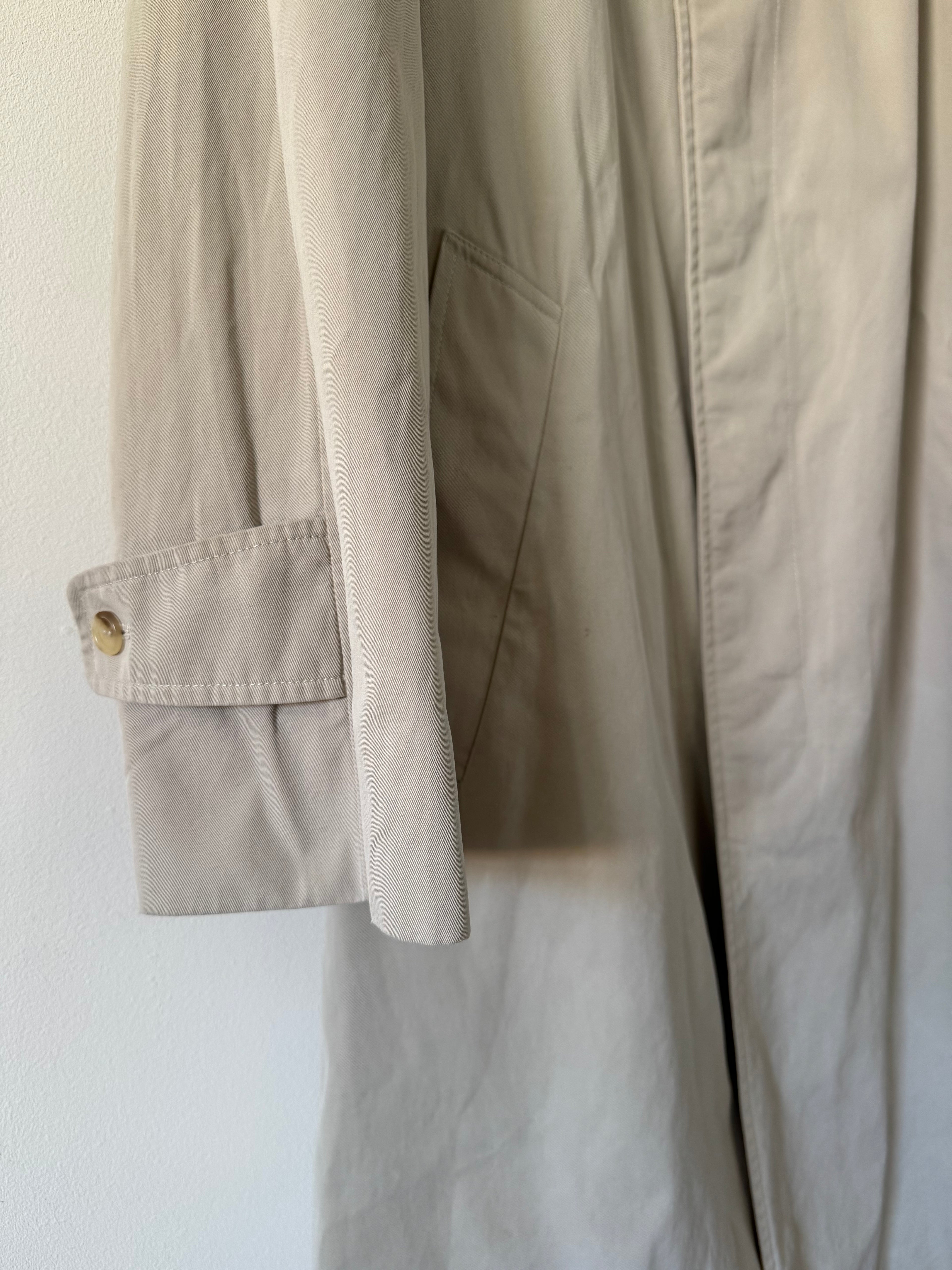 Close-up of beige trench with a button on a white background