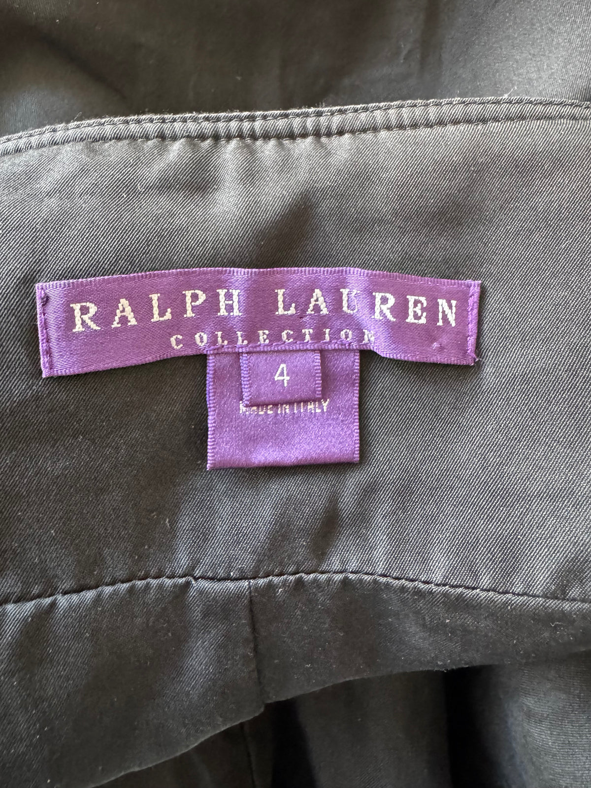 Close-up of a Ralph Lauren Collection garment label sewn onto dark gray fabric, with a size 4 tag below it.