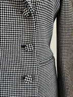 Close-up of a black and white micro-check patterned fabric, showing the texture and a button detail.