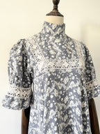 Gray floral dress with lace details on a mannequin against a white background