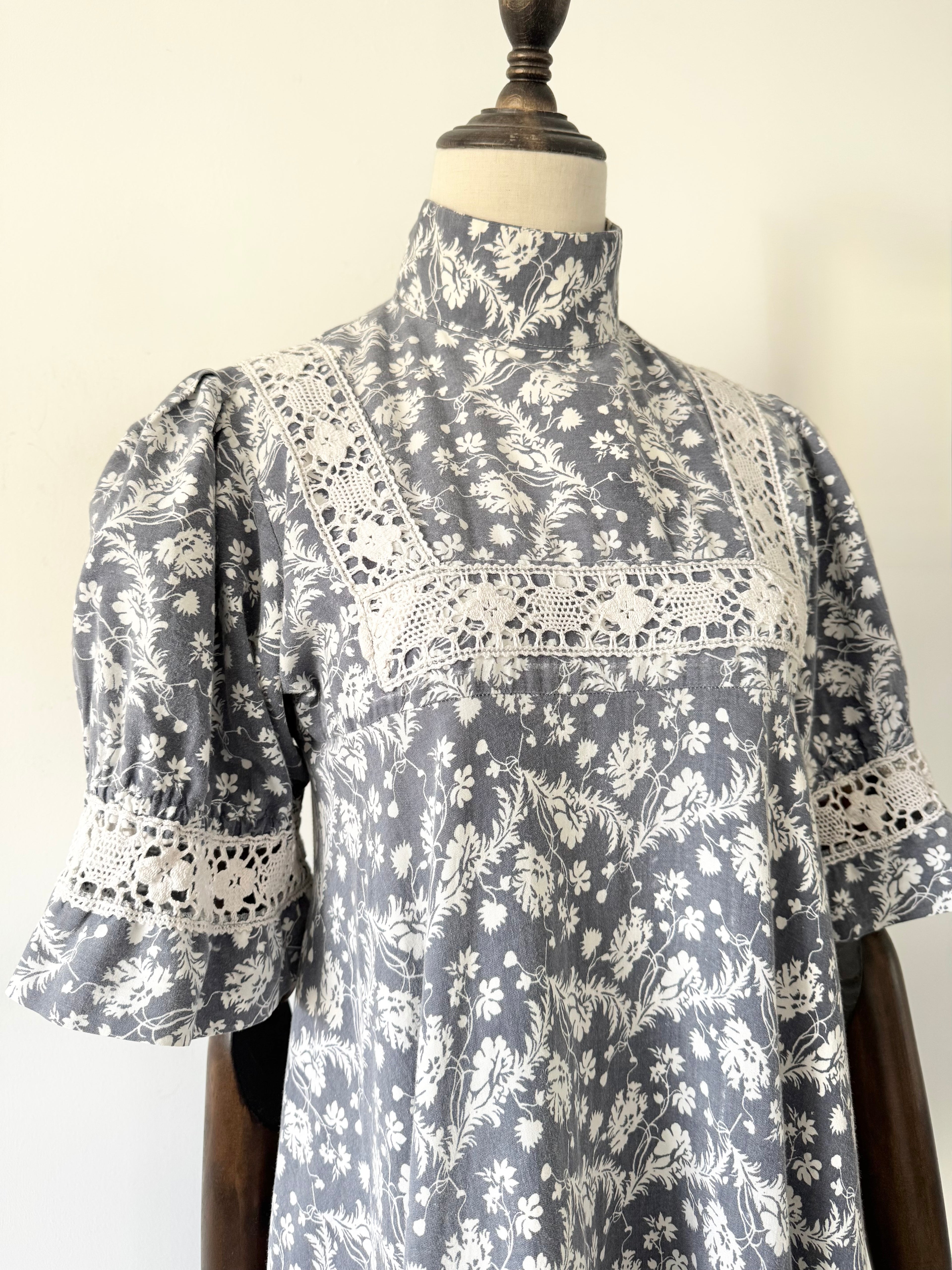 Gray floral dress with lace details on a mannequin against a white background