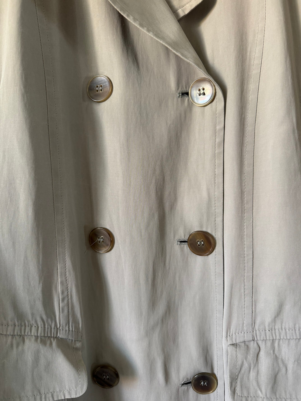 Close-up of trench coat with buttons on a light background