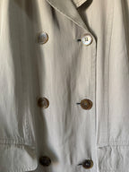 Close-up of trench coat with buttons on a light background