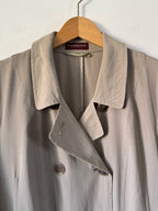 Beige trench coat on a hanger against a white background