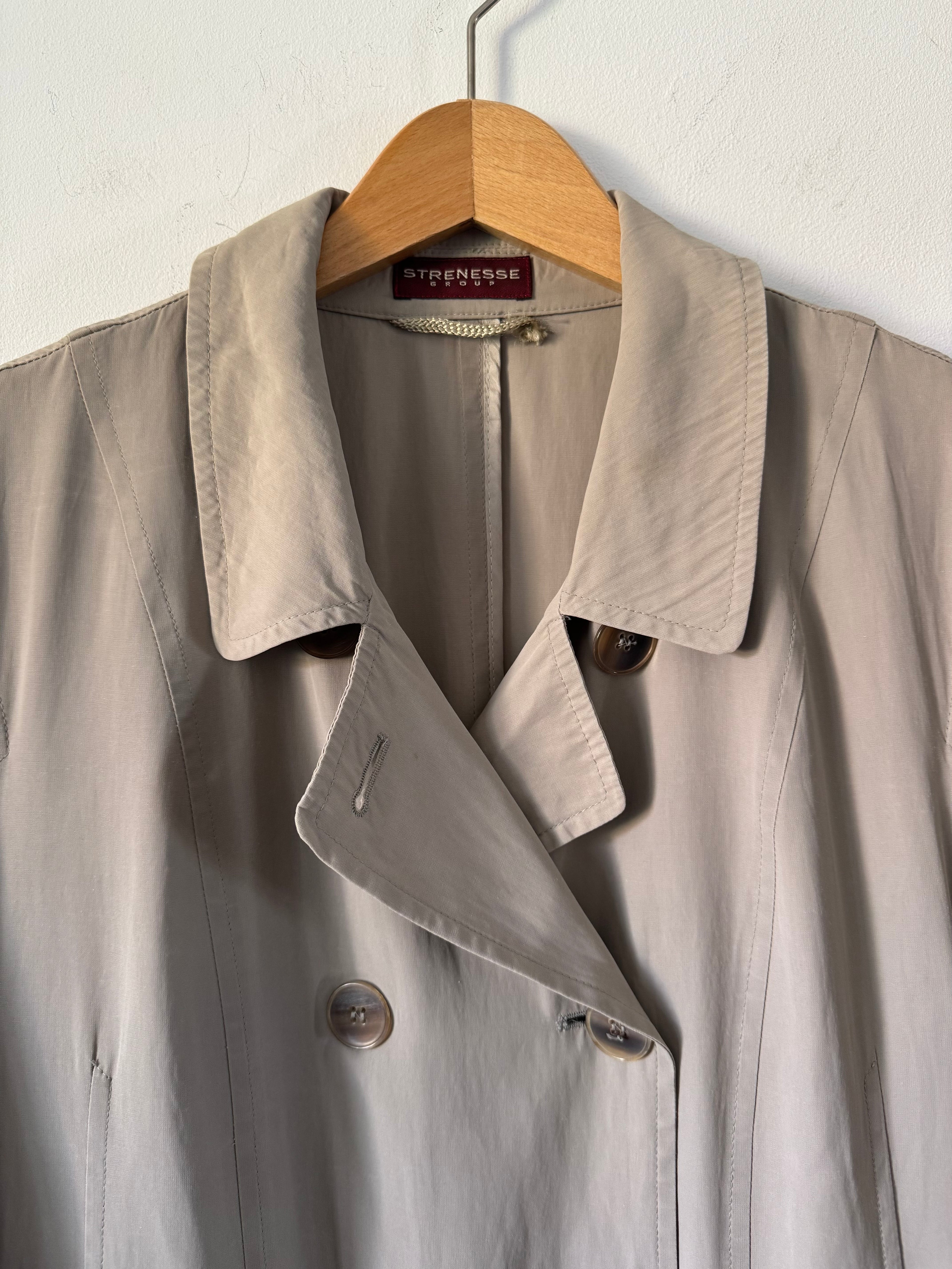 Beige trench coat on a hanger against a white background