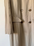 Close-up of a beige trench coat with buttons on a white background
