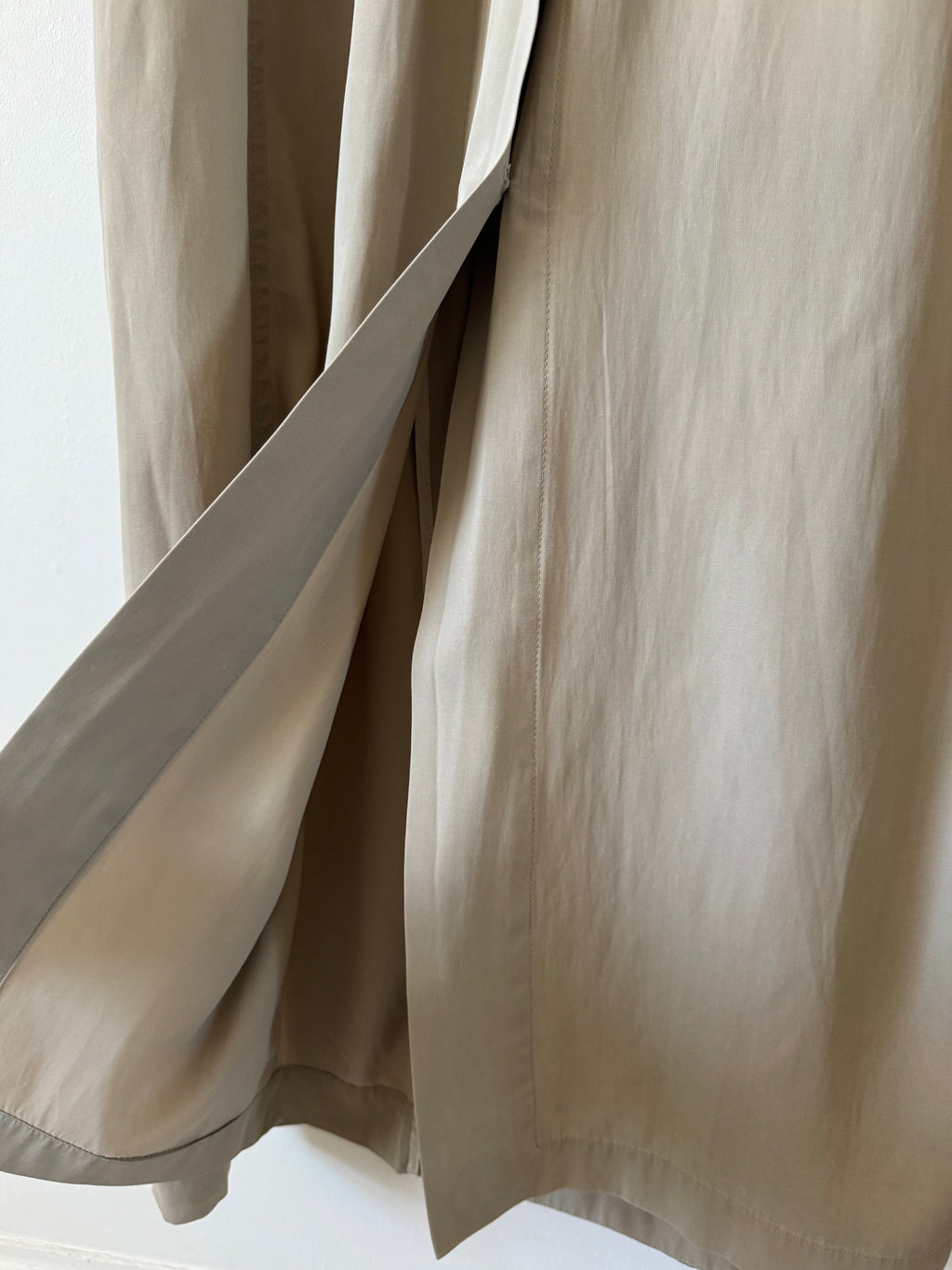 Close-up of beige trench coat with a neutral background