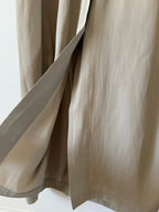 Close-up of beige trench coat with a neutral background