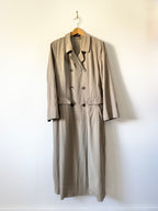 Beige trench coat on a hanger against a white wall