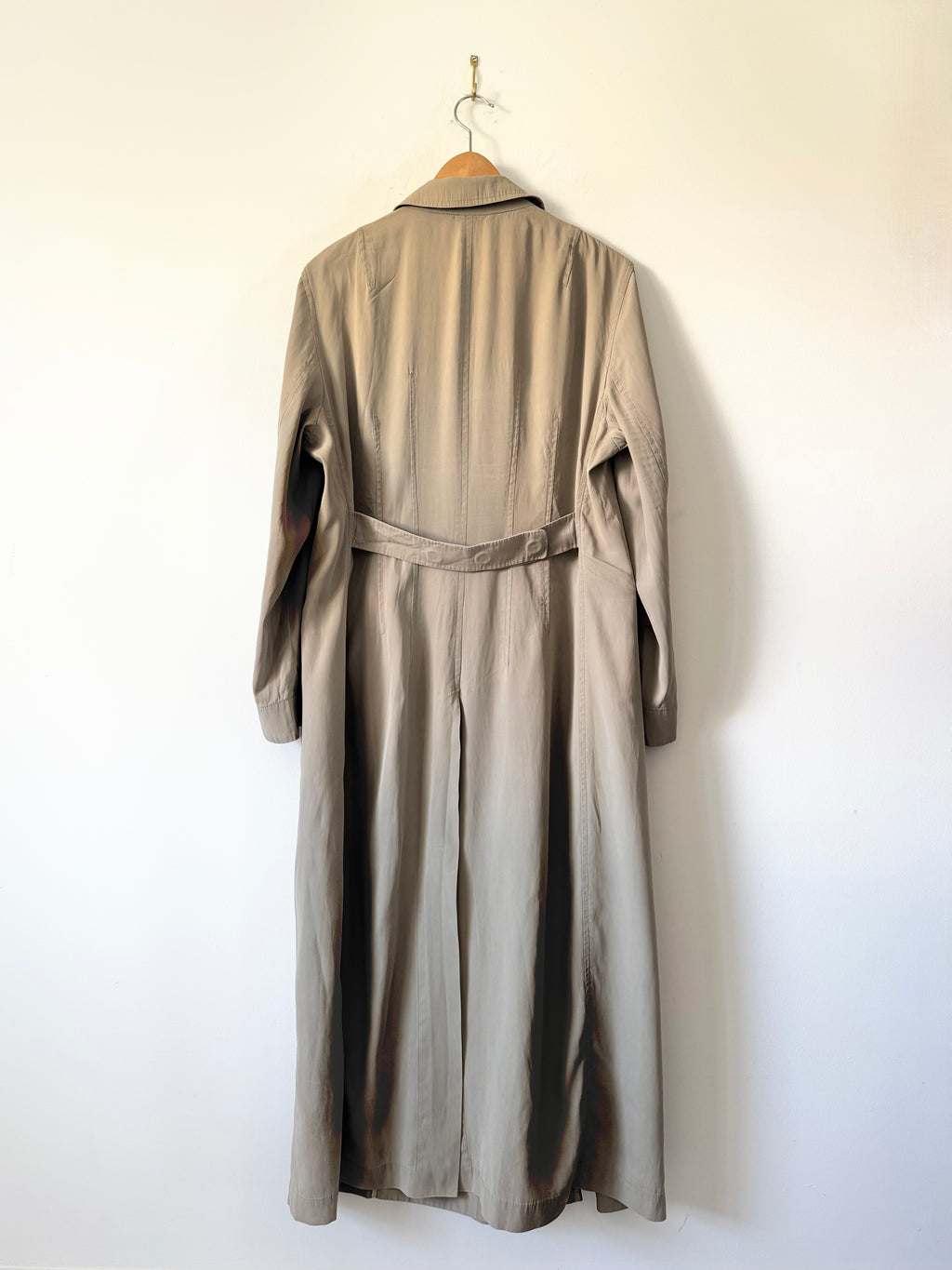Long beige coat on a hanger against a white wall