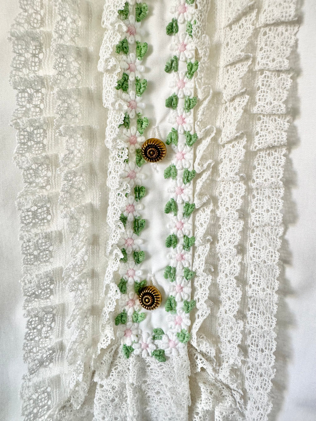 Decorative lace trim with floral patterns and buttons on a textured white background