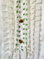 Decorative lace trim with floral patterns and buttons on a textured white background