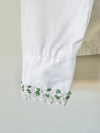 Close-up of a white garment with floral embroidery on a neutral background