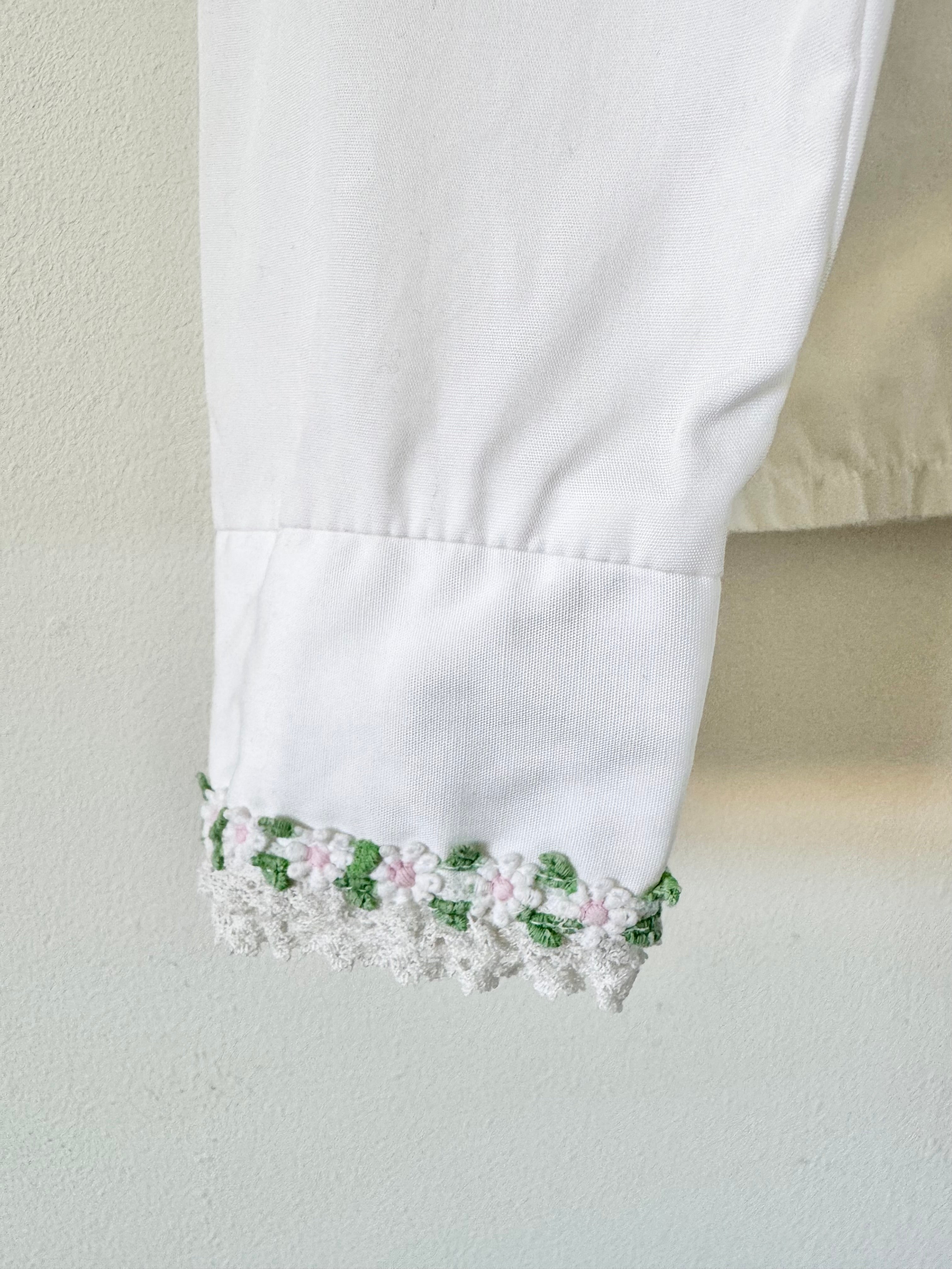 Close-up of a white garment with floral embroidery on a neutral background