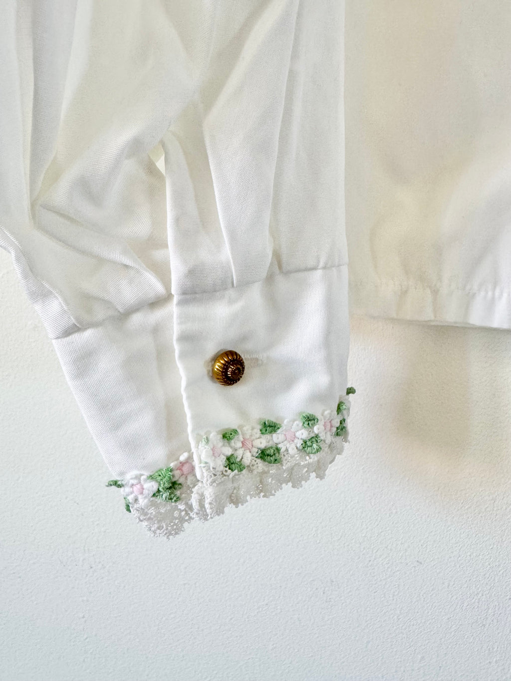 Close-up of a white blouse with floral embroidery on a light background