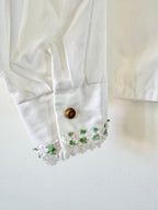 Close-up of a white blouse with floral embroidery on a light background
