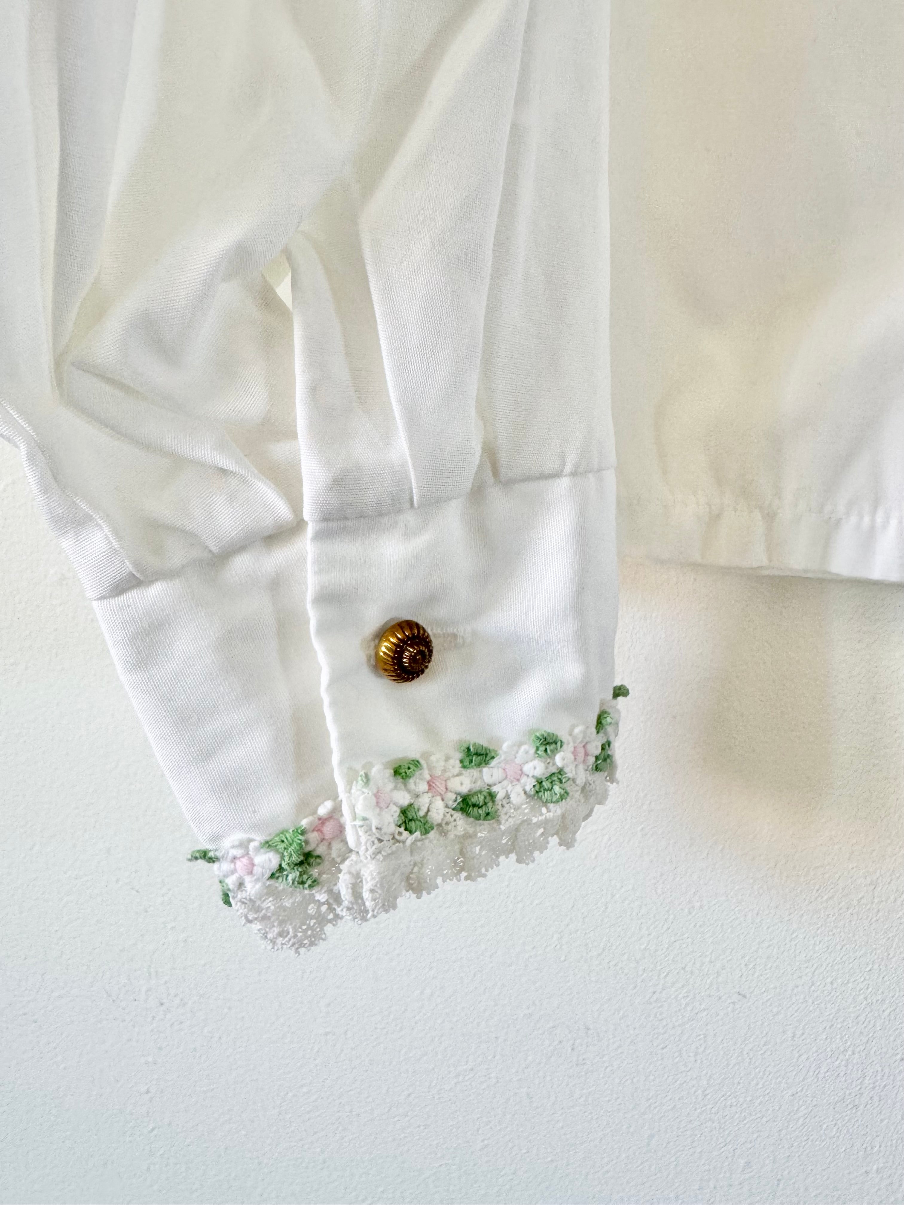 Close-up of a white blouse with floral embroidery on a light background