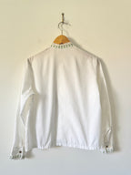 White blouse with lace details on a hanger against a white background